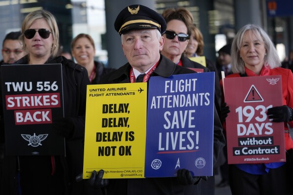 Flight attendants and a pilot protest at O'Hare International Airport in Chicago, Tuesday, Feb. 13, 2024. Three separate unions representing flight attendants at major U.S. airlines are picketing and holding rallies at 30 airports on Tuesday as they push for new contracts and higher wages. (AP Photo/Nam Y. Huh)