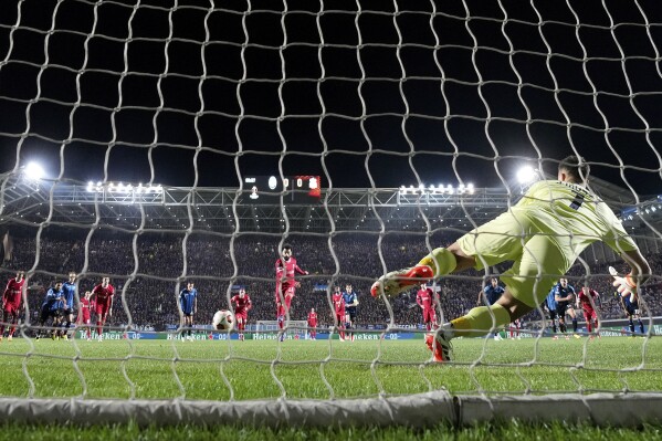 Liverpool's Mohamed Salah, center, scores the opening goal from the penalty spot past Atalanta's goalkeeper Juan Musso during the Europa League quarterfinal, second leg, soccer match between Atalanta and Liverpool at the Stadio di Bergamo, in Bergamo, Italy, Thursday, April 18, 2024. (AP Photo/Antonio Calanni)