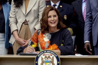 FILE - Gov. Gretchen Whitmer signs the largest state budget in Michigan's history on July 31, 2023, at the Wyandotte Fire Department, in Wyandotte, Mich. The mother of a Michigan man accused of making death threats on social media against Democratic politicians, including Whitmer, is now facing federal charges, according to an indictment unsealed Tuesday, Aug. 8, accusing her of lying when she purchased firearms that were later found in her son's possession. (Jake May/MLive.com/The Flint Journal via AP, File)
