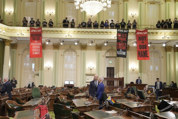 Assembly members Heath Flora, R-Modesto, left, and Josh Lowenthal, D-Long Beach, right, leave the Assembly chambers as protesters call for a cease-fire in Gaza disrupt the first day of the California legislative session in Sacramento, Calif., Wednesday, Jan. 3, 2024. The Assembly session was just getting started when protesters wearing matching black t-shirts stood up in the gallery and started singing "Cease-fire now" and "Let Gaza Live." The Assembly adjourned the session.(AP Photo/Rich Pedroncelli)