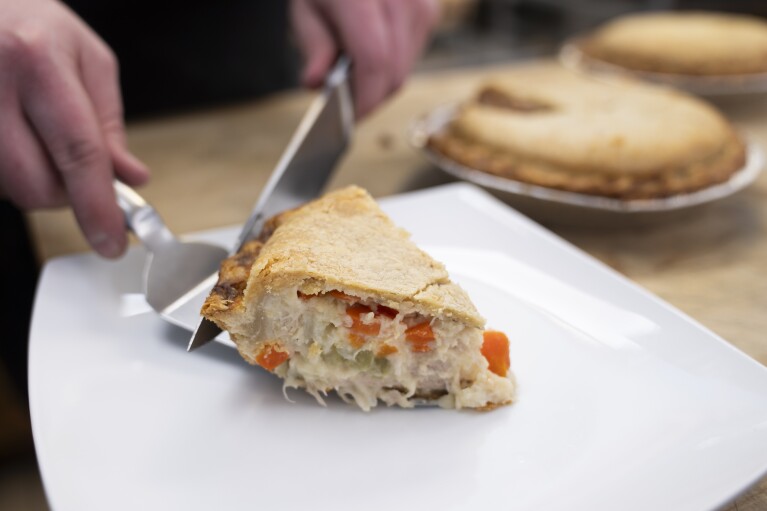 A freshly sliced piece of chicken pot pie is plated on a counter at Michele's Pies, Wednesday, March 13, 2024, in Norwalk, Conn. Math enthusiasts and bakers celebrate Pi Day on March 14 or 3/14, the first three digits of a mathematical constant with many practical uses. Around the world many people will mark the day with a slice of sweet or savory pie. (AP Photo/John Minchillo)