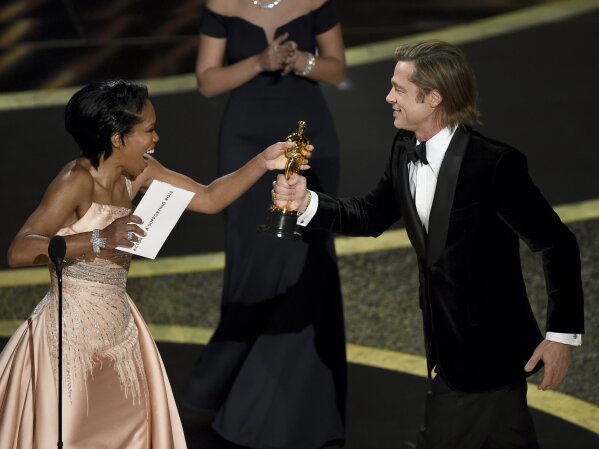 Regina King, left, presents Brad Pitt with the award for best performance by an actor in a supporting role for "Once Upon a Time in Hollywood" at the Oscars on Sunday, Feb. 9, 2020, at the Dolby Theatre in Los Angeles. (AP Photo/Chris Pizzello)