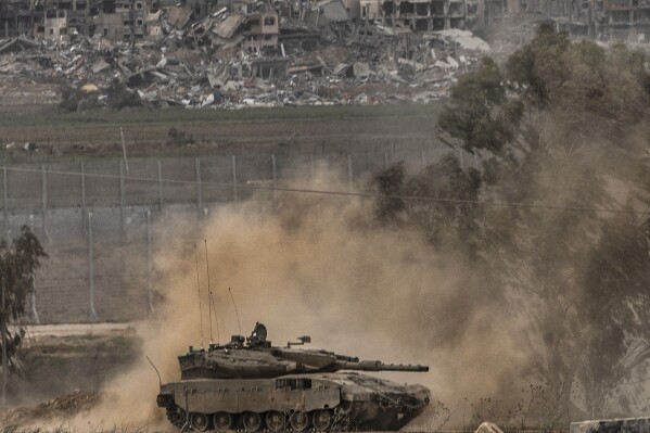 An Israeli army tank moves near the Gaza Strip border, in southern Israel, Saturday, Dec. 23, 2023. The army is battling Palestinian militants across Gaza in the war ignited by Hamas' Oct. 7 attack into Israel. Smoke from an Israeli bombardment is seen in background. (AP Photo/Tsafrir Abayov)