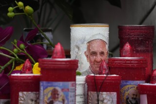 Rain falls on the auspicious candles with images of Pope Francis left outside the Agostino Gemelli Polyclinic, where he is being treated for bilateral pneumonia in Rome, Monday, Feb. 24, 2025. (AP Photo/Gregorio Borgia)