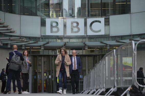 People walk outside the BBC Headquarters in London, Tuesday, Oct. 18, 2022 as the BBC is celebrating 100 years of broadcasting. The corporation marks its centenary Tuesday,  a century on from when it was founded in 1922 under its original name, The British Broadcasting Company. (AP Photo/Kin Cheung)
