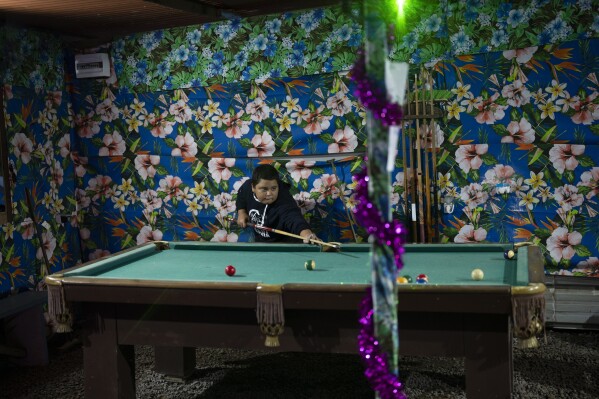 Children play pool at a snack bar in Te Aupoo, Tahiti, French Polynesia, Tuesday, Jan. 16, 2024. (AP Photo/Daniel Cole)