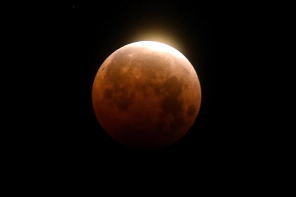 FILE - Light shines from a total lunar eclipse over Santa Monica Beach in Santa Monica, Calif., Wednesday, May 26, 2021. A total lunar eclipse will grace the night skies this weekend, providing longer than usual thrills for stargazers across North and South America. The celestial action unfolds Sunday night, May 15, 2022 into early Monday morning, with the moon bathed in the reflected red and orange hues of Earth’s sunsets and sunrises for about 1 1/2 hours, the longest totality of the decade. It will be the first so-called blood moon in a year.(AP Photo/Ringo H.W. Chiu)