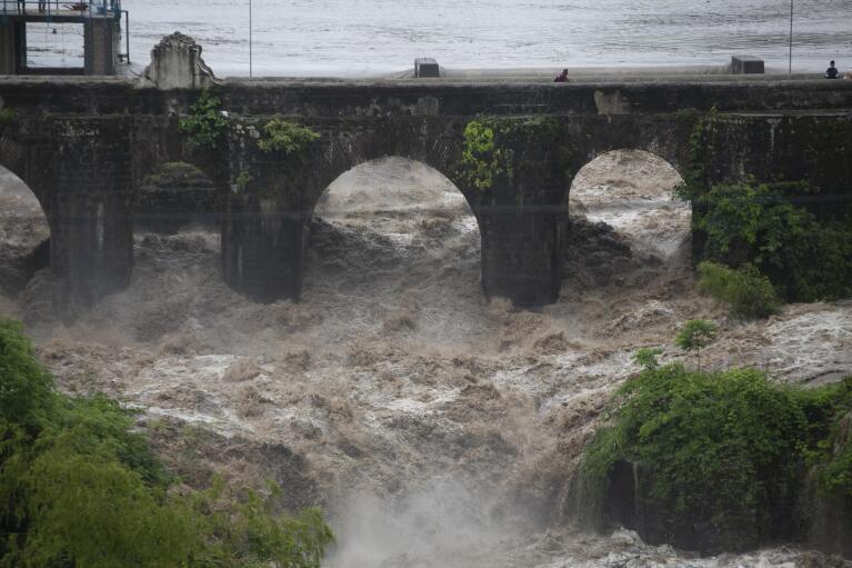 FILE - The swollen Los Esclavos River flows violently under a bridge during Tropical Storm Amanda in Cuilapa, eastern Guatemala, May 31, 2020. Global warming is altering the intensity and frequency of extreme weather events, such as El Nino and La Nina, the natural variations in temperatures in parts of the Pacific Ocean. (AP Photo/Moises Castillo, File)
