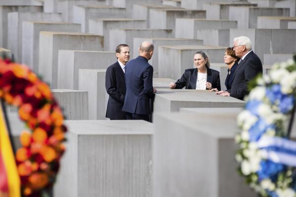 Israeli President Isaac Herzog, left, his wife Michal Herzog, 3rd left, German President Frank-Walter Steinmeier, right, and his wife Elke Buedenbender, 2nd right, and Deputy director of the Holocaust memorial Ulrich Baumann, 2nd left, talk together after a wreath laying ceremony at the Holocaust memorial in Berlin, Germany, Tuesday, Sept. 6, 2022. (AP Photo/Christoph Soeder)