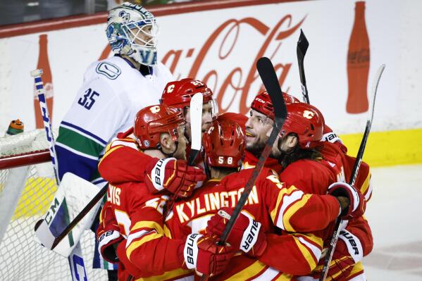 Vancouver Canucks goalie Thatcher Demko, left, waits as Calgary Flames celebrate a goal during the third period of an NHL hockey game Saturday, April 23, 2022, in Calgary, Alberta. (Jeff McIntosh/The Canadian Press via AP)
