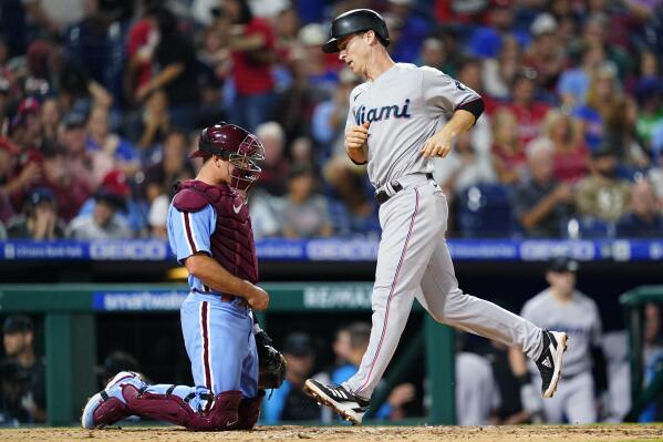 Miami Marlins' Joey Wendle, right, scores past Philadelphia Phillies catcher J.T. Realmuto after hitting a home run during the fifth inning of a baseball game, Thursday, Sept. 8, 2022, in Philadelphia. (AP Photo/Matt Slocum)
