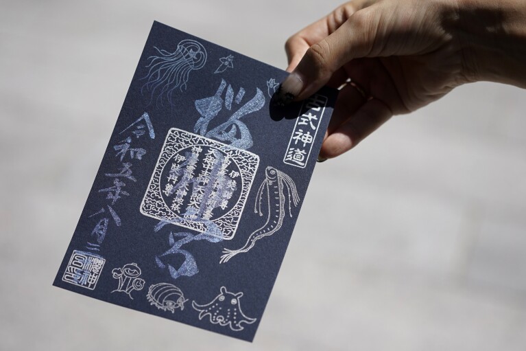 Momo Nomura, a graphic artist and entrepreneur, shows a newly collected Goshuin, a seal stamp certifying her visit that comes with elegant calligraphy and the season’s drawings, at Sakura Jingu shrine in Tokyo on Aug. 30, 2023. (AP Photo/Eugene Hoshiko)