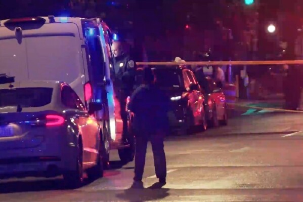 In this image taken from video provided by WJLA, a bystander watches as law enforcement works the scene after two staff members of the Israeli embassy in Washington were shot and killed outside the Capital Jewish Museum on Wednesday, May 21, 2025, in Washington. (WJLA via AP)