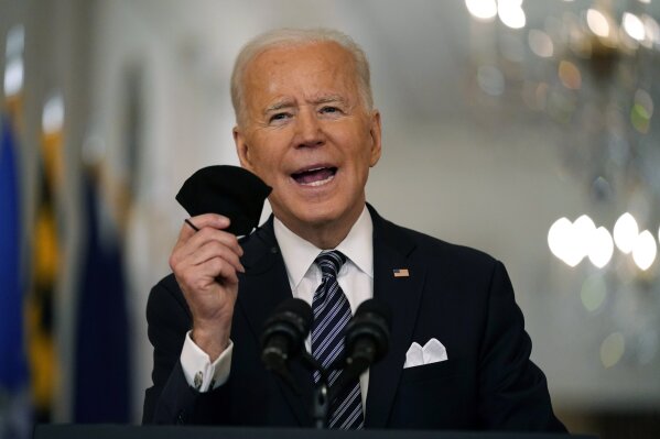 President Joe Biden holds up his face mask as he speaks about the COVID-19 pandemic during a prime-time address from the East Room of the White House, Thursday, March 11, 2021, in Washington. (AP Photo/Andrew Harnik)