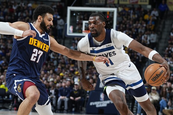 Minnesota Timberwolves center Naz Reid, right, drives against Denver Nuggets guard Jamal Murray during the second half of an NBA basketball game Wednesday, April 10, 2024, in Denver. (AP Photo/David Zalubowski)