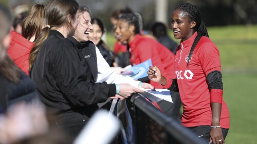 Canadian player Nichelle Prince signs a poster for a fan after practice ahead of the Women's World Cup in Melbourne, Australia, Monday, July 17, 2023. Canada held a public training session ahead of its opening match with players from Melbourne-based Heidelberg United FC watching the Olympic champions practice on their field, preparing for Friday July 21, 2023 game against Nigeria. (AP Photo/Victoria Adkins)