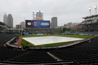 A tarp covers the infield as the start of a baseball game between the Cincinnati Reds and the Cleveland Guardians is delayed by rain Wednesday, May 18, 2022, in Cleveland. (AP Photo/Ron Schwane)