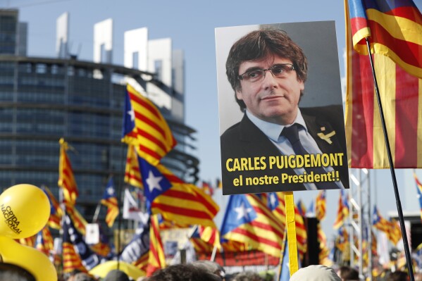 FILE - Demonstrators hold a poster of former Catalan regional president Carles Puigdemont outside the European Parliament in Strasbourg, eastern France, on July 2, 2019. Nearly six years ago, the leader of Catalonia's failed secession bid slipped secretly across the Spanish border to escape arrest and start a life of a self-styled political exile. Now, Carles Puigdemont, after eluding repeated extradition attempts by Spanish justice, has the future of Spain’s government in his hands. (AP Photo/Jean-Francois Badias, File)
