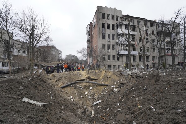 Municipal workers clear the rubble in front of a residential building damaged by a Russian missile strike in Kharkiv, Ukraine, Tuesday, Jan. 2, 2024. (AP Photo/Andrii Marienko)