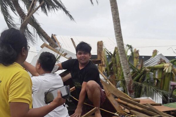 
              This Thursday, Oct. 25, 2018 photo provided by Jan Reyes shows Billy Tuazon siting on a pile of debris in Saipan, Northern Mariana Islands, as the two other men help move the pile left behind after Super Typhoon Yutu devastated the U.S. Pacific territory. Tuazon was trapped under the debris for several hours after the storm hit through the Commonwealth of the Northern Mariana Islands earlier in the week. (Jan Reyes via AP)
            