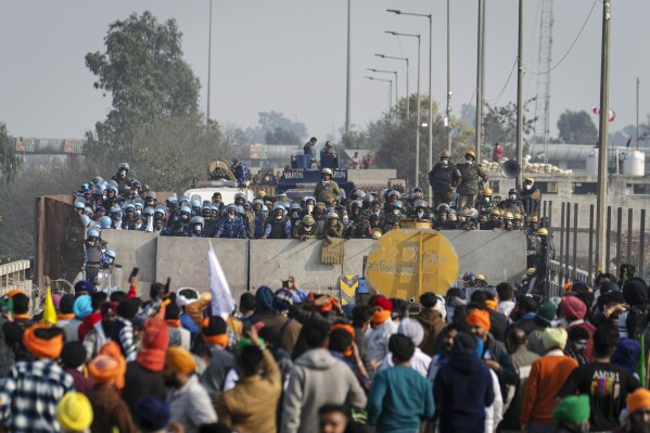 Protesting farmers face the police across a barricade near Shambhu border that divides northern Punjab and Haryana states, almost 200 kilometers (125 miles) from New Delhi, India, Friday, Feb.16, 2024. Farmers are blocking highways and holding demonstrations in many rural areas in northern India to protest over a range of grievances that have also led tens and thousands to march toward the capital. (AP Photo/Altaf Qadri)