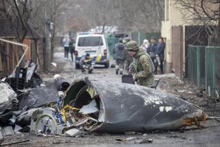 Un soldado ucraniano inspecciona los restos de un avión derribado, el viernes 25 de febrero de 2022,  en Kiev, Ucrania. (AP Foto/Vadim Zamirovsky)