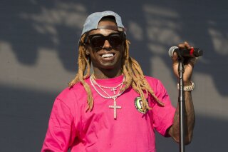 FILE - In this June 16, 2018, file photo, Lil Wayne performs on Day 3 of the 2018 Firefly Music Festival at The Woodlands in Dover, Del. Rapper Lil Wayne has been charged with possession of a firearm by a convicted felon, an offense that carries a potential sentence of up to 10 years in prison. Documents filed Tuesday, Nov. 17, 2020,  in Miami federal court say the rapper, whose real name is Dwayne Michael Carter Jr., had a gun and ammunition on Dec. 23 of last year despite knowing he had the previous felony.  (Photo by Owen Sweeney/Invision/AP, File)