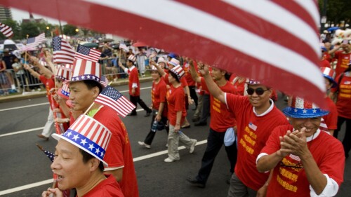 FILE - Tang De Wong, lower left, and other members of the Chinese Benevolent Association march in an Independence Day parade in Philadelphia, July 4, 2008. Flags proliferate every July Fourth, but it wasn't always a revered and debated symbol. Unlike the right to assemble or trial by jury, the flag's role was not prescribed by the founders: Flags would have been rare during early Independence Day celebrations and were so peripheral to early U.S. history that no original flag exists. (AP Photo/Matt Rourke, File)