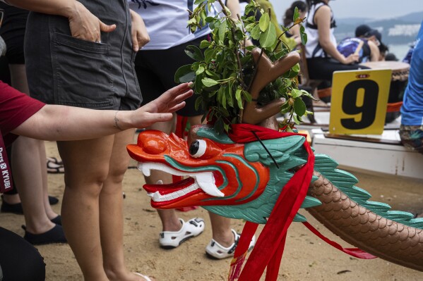 A competitor touches the dragon's head before the race in the Stanley International Dragon Boat Championships to celebrate the Dragon Boat Festival in Hong Kong, Saturday, May 31, 2025. (AP Photo/Chan Long Hei)