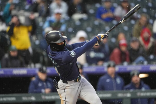 Seattle Mariners' Julio Rodríguez follows through with his swing after connecting for an RBI single off Colorado Rockies starting pitcher Dakota Hudson in the fourth inning of a baseball game Saturday, April 20, 2024, in Denver. (AP Photo/David Zalubowski)