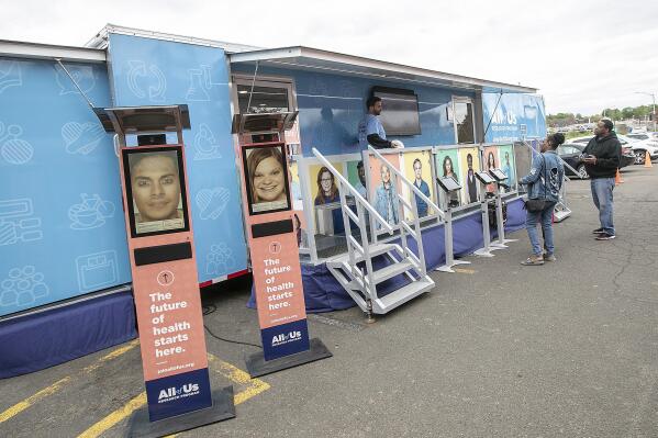 FILE - People stand by the All of Us Mobile Education and Enrollment Center at the Community Health Center on State Street in Meriden, Conn., May 13, 2019. Thousands of Americans who shared their DNA for science are about to learn something in return: if they harbor some problematic genes. It's part of a massive National Institutes of Health project to unravel how people's genetics, environments and habits interact to mold their health. (Dave Zajac/Record-Journal via AP, file)