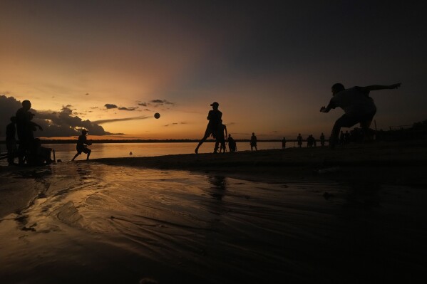 Residents play ball at sunset on the sands of the Tocantis River, in the city of Mocajuba, Para state, Brazil, Friday, June 2, 2023. (AP Photo/Eraldo Peres)
