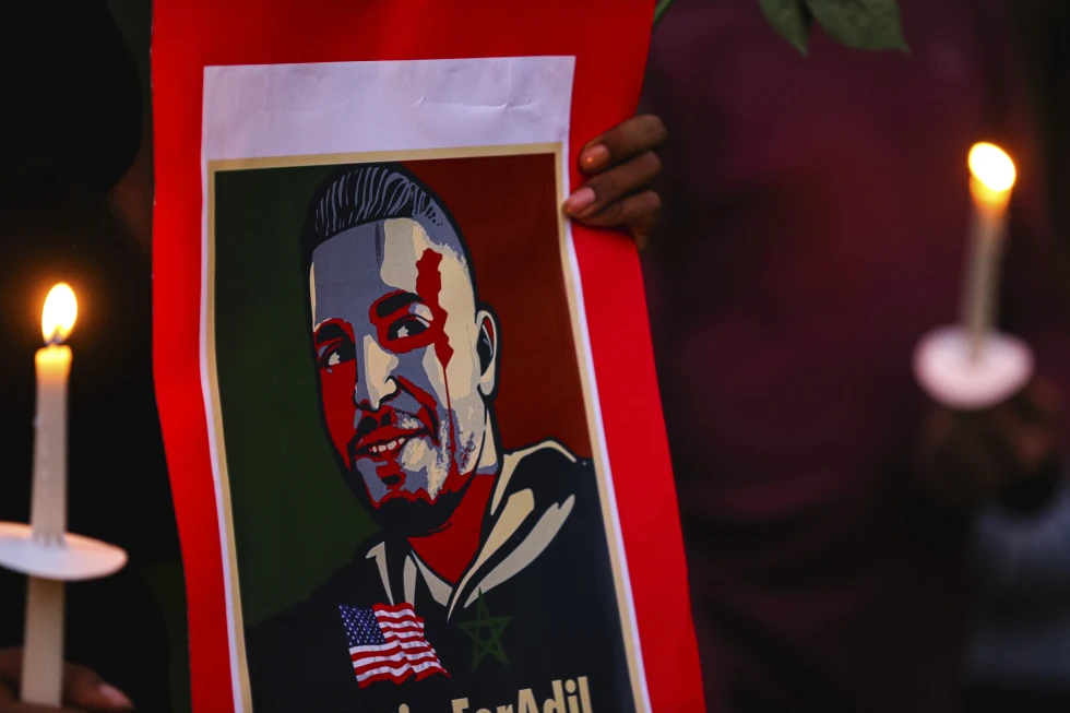 An attendee holds a poster of Adil Dgoughi at a vigil in Martindale, Texas on Oct. 24, 2021.