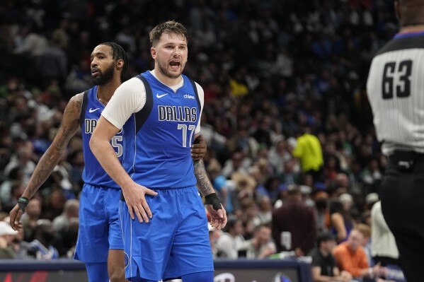 Dallas Mavericks guard Luka Doncic (77) is held by teammate Derrick Jones Jr. while disputing a call to referee Derek Richardson (63) during the second half of an NBA basketball game against the Oklahoma City Thunder in Dallas, Saturday, Dec. 2, 2023. (AP Photo/LM Otero)