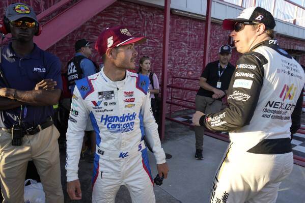Kyle Larson, center, talks with Brad Keselowski, right, after arriving for the NASCAR All-Star auto race at North Wilkesboro Speedway in North Wilkesboro, N.C., Sunday, May 19, 2024. (AP Photo/Chuck Burton)