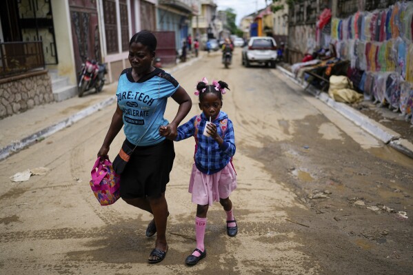 A child sips on a drink after she was picked up from school, in Cap-Haitien, Haiti, Wednesday, April 17, 2024. (AP Photo/Ramon Espinosa)