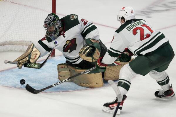 Minnesota Wild right wing Brandon Duhaime reaches for a loose puck as goaltender Marc-Andre Fleury reaches back to make a save during the third period of an NHL hockey game, Thursday, Oct. 27, 2022 in Ottawa, Ontario. (Adrian Wyld/The Canadian Press via AP)