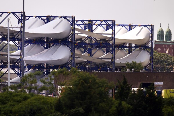 FILE - Giant wind turbine blades for the Vineyard Winds project are stacked on racks in the harbor, July 11, 2023, in New Bedford, Mass. Vineyard Wind said Tuesday, July 16, 2024, that it is working to recover debris on Nantucket's southern-facing beaches after one of the wind turbine blades suffered damage last weekend. (AP Photo/Charles Krupa, File)