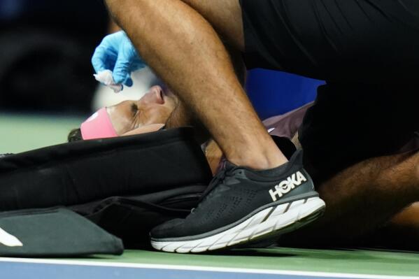 Rafael Nadal, of Spain, is treated by a trainer during a medical timeout during a match against Fabio Fognini, of Italy, during the second round of the U.S. Open tennis championships, early Friday, Sept. 2, 2022, in New York. Nadal's racket head rebounded off the court and hit his nose. (AP Photo/Frank Franklin II)
