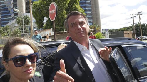 Former Brazilian President Jair Bolsonaro leaves after giving testimony over the Jan. 8 attacks on government buildings, at Federal Police headquarters in Brasilia, Brazil, Wednesday, April 26, 2023. Thousands of Bolsonaro supporters trashed the presidential palace, the Supreme Court and Congress one week into President Luiz Inácio Lula da Silva's third term in office. At left is a police agent. (AP Photo/Gustavo Morteno)