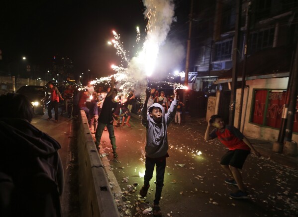 FILE - Youths light firecrackers and flares as they celebrate the end of the fasting month of Ramadan on a street in Jakarta, Indonesia, Tuesday, June 4, 2019. Islam follows a lunar calendar and so Ramadan and Eid cycle through the seasons. In 2024, the first day of Eid al-Fitr is expected to be on or around April 10; the exact date may vary among countries and Muslim communities. (AP Photo/Dita Alangkara, File)