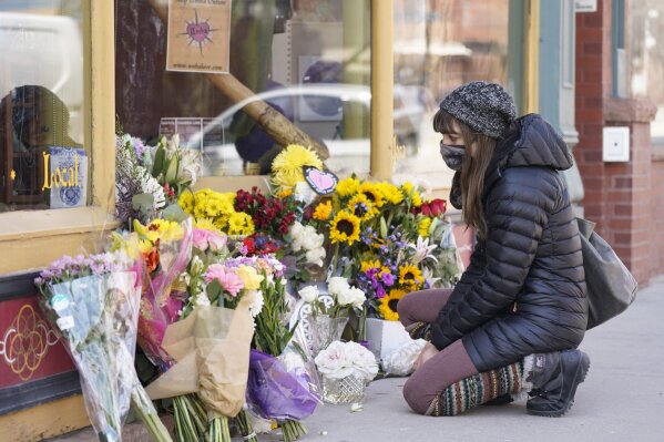 Jacqui Mirell of Boulder, Colo., looks at a tribute outside the store owned by one of 10 victims in the mass shooting at a King Soopers grocery store Wednesday, March 24, 2021, in Boulder, Colo. A shrine filled with candles and flowers kept growing Wednesday outside Umba Love, the clothing and accessories shop that victim Tralona Bartkowiak ran with her sister on Boulder’s popular Pearl Street Mall. Bartkowiak died in the supermarket shooting attack on Monday. (AP Photo/David Zalubowski)