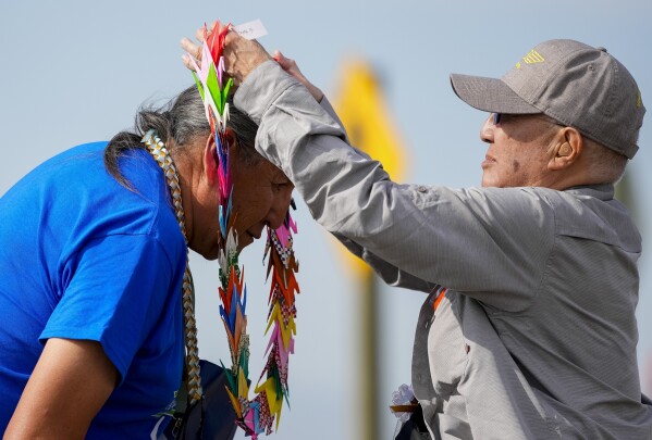 Minidoka survivor and member of the pilgrimage planning committee Paul Tomita, right, gives a wreath of origami cranes to Hubert B. Two Leggins, an original member of the Whistling Water Clan from the Black Lodge District, following a blessing during a closing ceremony for the Minidoka Pilgrimage at the Minidoka National Historic Site, Sunday, July 9, 2023, in Jerome, Idaho. (AP Photo/Lindsey Wasson)