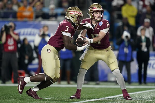 Florida State quarterback Brock Glenn (11) hands off the ball to running back Trey Benson (3) during the first half of the Atlantic Coast Conference championship NCAA college football game against Louisville, Saturday, Dec. 2, 2023, in Charlotte, N.C. (AP Photo/Erik Verduzco)
