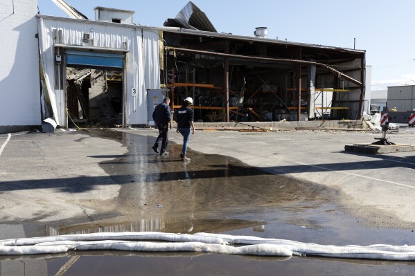 FILE - A Massachusetts Department of Environmental Protection worker walks in front of the damaged Seqens plant after crews removed chemicals, May 5, 2023, in Newburyport, Mass. The federal Occupational Safety and Health Administration has found the explosion that killed one worker at the pharmaceutical chemical plant could have been prevented and proposed nearly $300,000 in penalties for numerous violations. (AP Photo/Michael Dwyer, file)