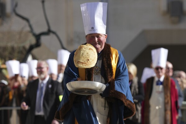 A competitor flips a pancake during a traditional pancake race by livery companies at the Guildhall in London, Tuesday, March 4, 2025. (AP Photo/Frank Augstein)