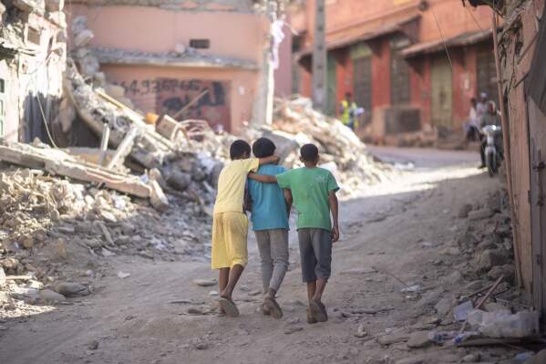 Children walk through the rubble of their town of Amizmiz which was damaged by the earthquake, outside Marrakech, Morocco, Thursday, Sept. 14, 2023. (AP Photo/Mosa'ab Elshamy)