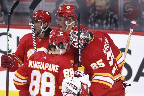 Calgary Flames goalie Jacob Markstron, right, and teammate Andrew Mangiapane (88) celebrate the team's 3-2 win over the Vancouver Canucks in an NHL hockey game Saturday, Dec. 31, 2022, in Calgary, Alberta. (Larry MacDougal/The Canadian Press via AP)