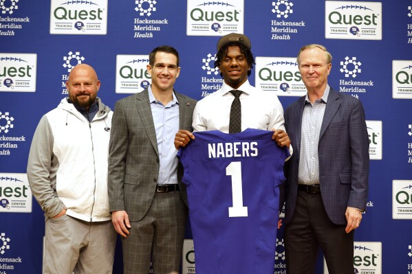 New York Giants first round draft pick Malik Nabers holds a jersey as he poses with head coach Brian Dabol, left, Giants' president John Mara, second from left, and general manager Joe Schoen, right, during an NFL football press conference, Friday, April 26, 2024, in East Rutherford, N.J. (AP Photo/Noah K. Murray)