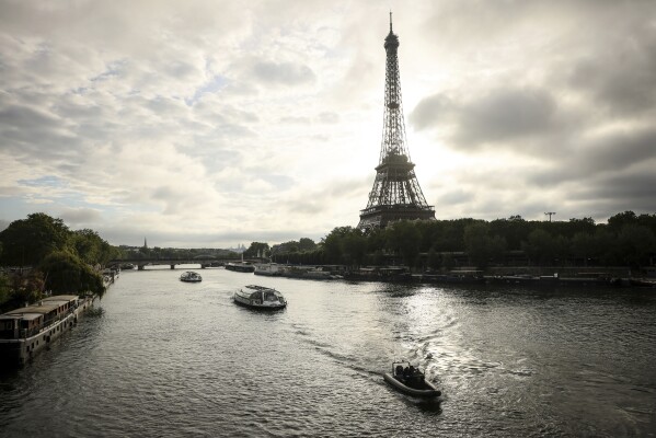 Barges cruise on the Seine river near the Eiffel Tower during a rehearsal for the Paris 2024 Olympic Games opening ceremony, Monday, June. 17, 2024 in Paris. The river will host the Paris 2024 Olympic Games opening ceremony on July 26 with boats for each national delegation. (AP Photo/Thomas Padilla)